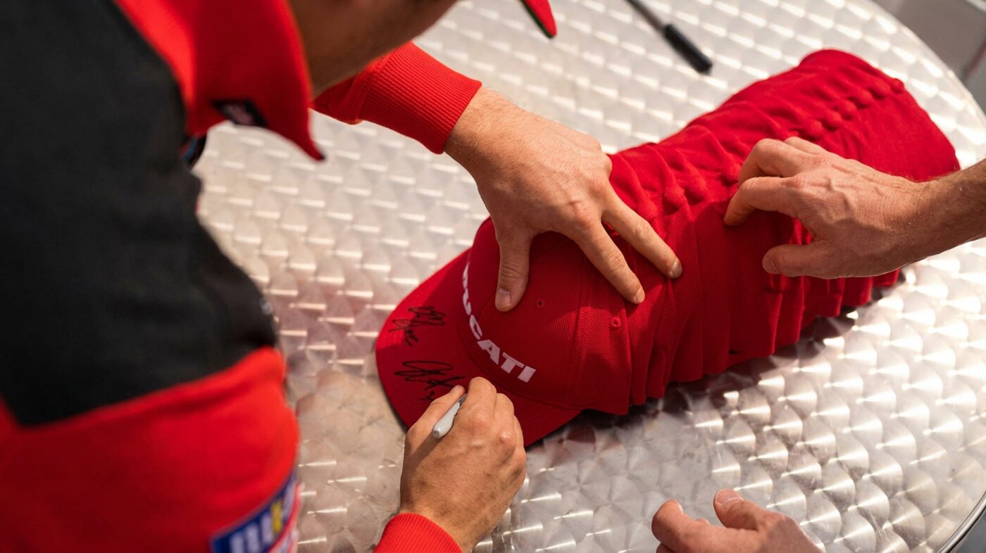 A hat being signed at a live event, with branded merchandise in use rather than in a box.