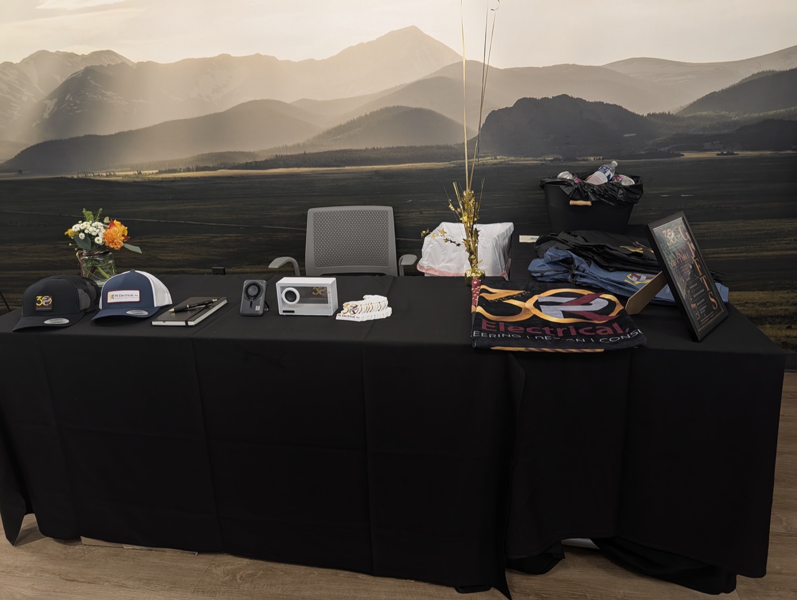 The gift table set before guests arrive: branded caps, a power bank, a Bluetooth speaker, a folded towel and a notebook and pen set, all carrying the 30-year mark.